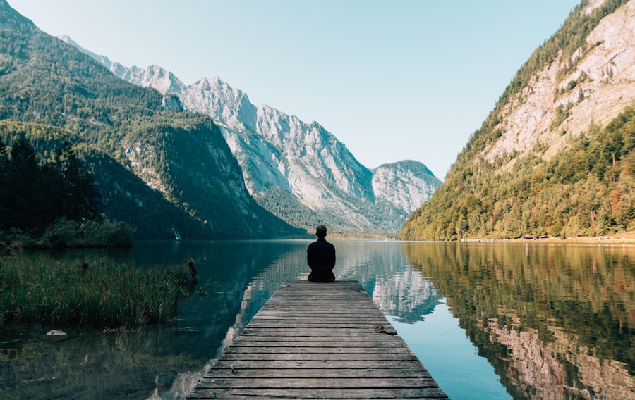 Mensch sitzt auf einem Steg am Bergsee